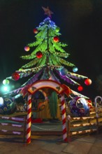 Children enjoying a carousel ride beneath a brightly lit christmas tree at a festive night market