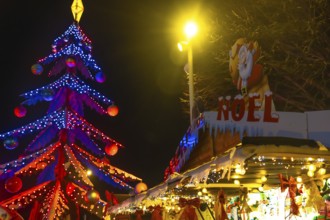 Glowing christmas tree and decorated market stall create festive atmosphere at night in bayonne,