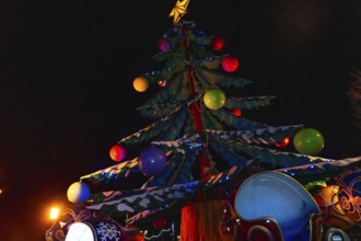 Colorful christmas tree with lights and decorations illuminating a carousel at night in bayonne,