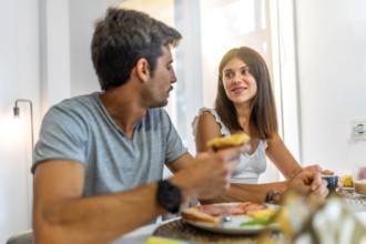 Young couple sharing a meal and conversation at their kitchen table, enjoying a relaxing morning