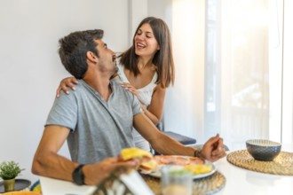 Young couple sharing a laugh during breakfast at home, enjoying a meal and each other's company in