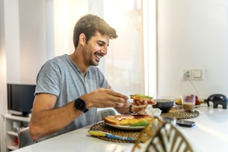 Young man smiling while enjoying a nutritious breakfast of avocado toast in a stylish, modern