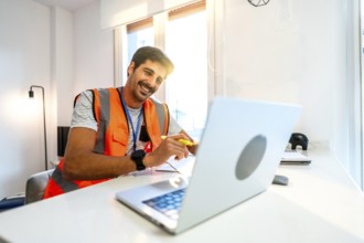 Young construction engineer wearing an orange safety vest working from home having a video