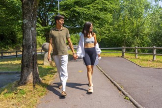 Happy couple enjoying a relaxing walk together in nature, holding hands and talking on a sunny