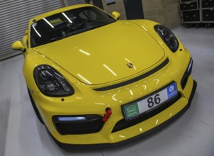 Dynamic photo front of sports car racing car yellow Porsche Cayman GT4 with front left mounted red