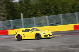 Yellow racing car sports car Porsche Cayman GT4 races at high speed top speed during trackday on