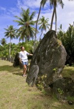 Tourist standing next to oversized huge stone coins real currency in stone money bank stone money