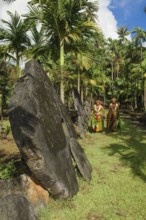 Native couple from Yap in traditional traditional costume walking on path through palm forest