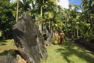 Native couple from Yap in traditional traditional costume walking on path through palm forest