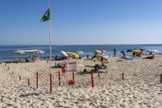 Kilometre-long sandy beach Praia do Barril, on the island off Santa Luzia, green flag indicates