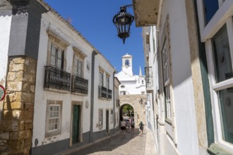 Faro, old town centre alley, R. do Municipio, view of the Arco da Vila city gate, Algarve, Portugal