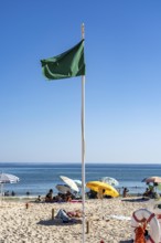 Kilometre-long sandy beach Praia do Barril, on the island off Santa Luzia, green flag indicates