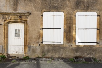 Door and 2 white, closed windows made of wood, historic house facade, yellow sandstone, Marville,