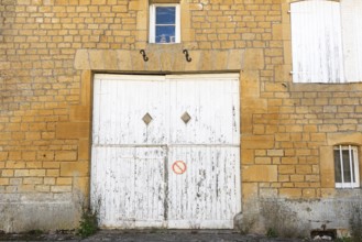 Closed white wooden door and windows, historic house façade, yellow sandstone, Marville,