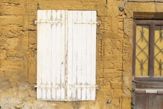 Closed door and white wooden window, historic house façade, yellow sandstone, Marville, Renaissance