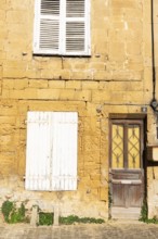 Closed door and white wooden window, historic house façade, yellow sandstone, Marville, Renaissance