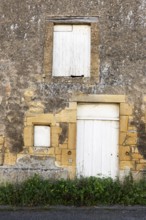 Closed white wooden door and windows, historic house façade, yellow sandstone, Marville,