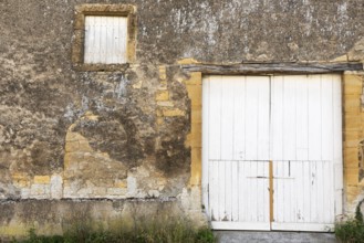 Closed white wooden door and windows, historic house façade, yellow sandstone, Marville,
