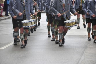 Men in traditional traditional costume play drums during a traditional Bavarian parade,