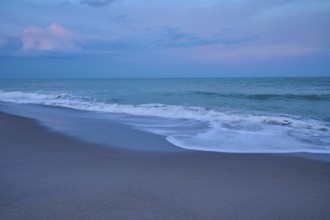 Beach at dusk with gentle waves and blue-grey sky, Cocoa Beach, Port Canaveral, Florida, USA