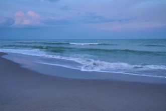 Tranquil beach landscape at dusk with gentle waves and blue sky, Cocoa Beach, Port Canaveral,