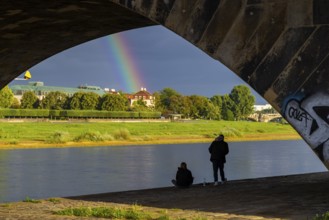 Young couple watching the rainbow over the Elbe at Neustädter Elbufer, Dresden, Saxony, Germany