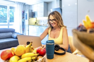 Young woman working remotely from her home office using laptop, enjoying healthy lifestyle with