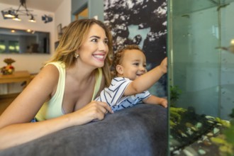 Happy mother and her baby son lying on the sofa, enjoying a delightful moment together while