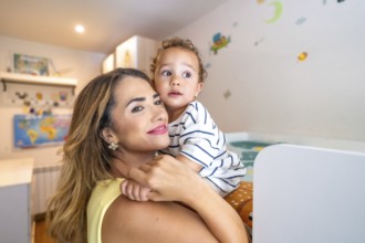 Loving mother cradling her baby son in his cozy bedroom, cherishing a sweet moment filled with