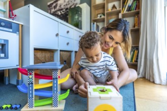 Happy mother and son enjoying playtime together, engaging with colorful educational toys in the