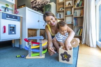 Smiling mother and her baby boy having fun together while playing with educational toys on the