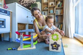 Happy mother and her cute son are playing together with colorful educational toys in a modern