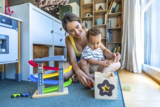 Happy mother and son playing together with educational wooden toys, enjoying quality time on the
