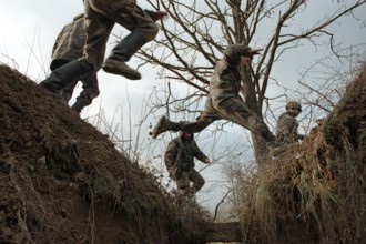 BIH, Bosnia, Brcko, 07.01.1996, Bosnian and American soldiers jump over a former trench
