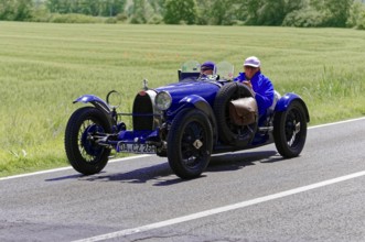 Blue vintage car with male occupants on rural road next to wheat fields, vintage car, car race,