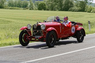 Red classic car with two men on a sunny road next to fields, classic car, car race, Mille Miglia,