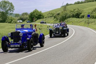 Two blue classic cars driving one behind the other on a winding country road, classic car, car