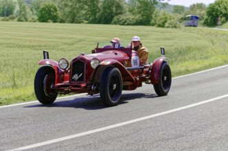A red classic car drives on a country road through a green landscape, classic car, car race, Mille