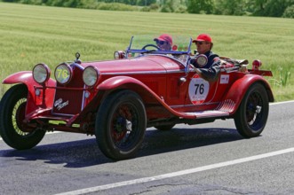 A classic red vintage car with two drivers on a country road, vintage car, car race, Mille Miglia,