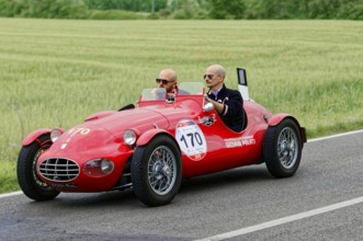 A classic red car with two people driving on a country road, classic car, car race, Mille Miglia,