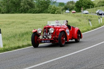 A red classic car with two drivers enjoys a drive in a picturesque landscape, classic car, car