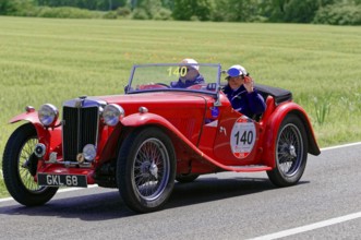 A red classic roadster drives along a rural road in fine weather, classic car, car race, Mille