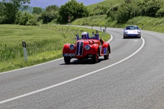 A sporty red vintage car followed by a modern vehicle on a road, vintage car, car race, Mille