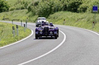 A purple vintage car followed by a white car on a country road, vintage car, car race, Mille
