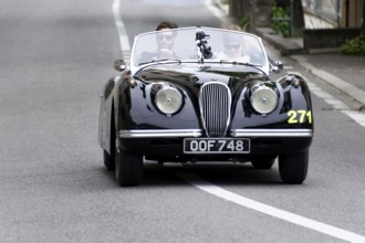 No. 271, Jaguar XK 120 OTS, model year 1953, black vintage convertible driving on a road with two