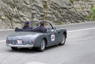 Grey vintage convertible driving on a road along rocky landscape, Mille Miglia 2014 or 1000 Miglia,