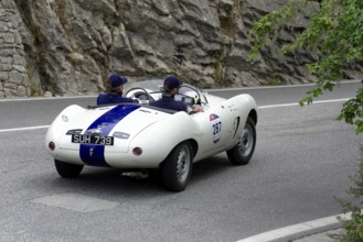 Two drivers drive a white vintage convertible with a blue stripe on a road, Mille Miglia 2014 or