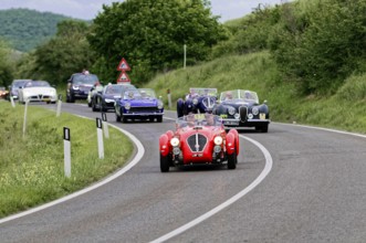 Group of classic cars driving in a row on a winding country road, classic car, car race, Mille