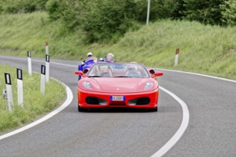 Red Ferrari convertible on winding road surrounded by green landscape, classic car, car race, Mille