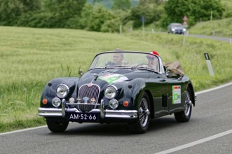 Black convertible driving on a country road through an idyllic landscape, classic car, car race,